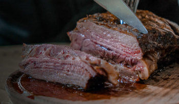 Image of a knife and fork slicing a thick cooked steak.