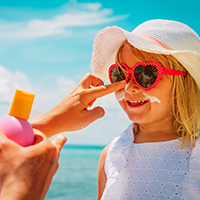 Mother applying suntan lotion on daughter face stock photo