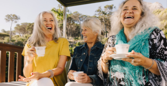 Senior women laughing happily while having tea together. Group of elderly friends enjoying their summer vacation at a spa resort. Three mature women enjoying themselves.