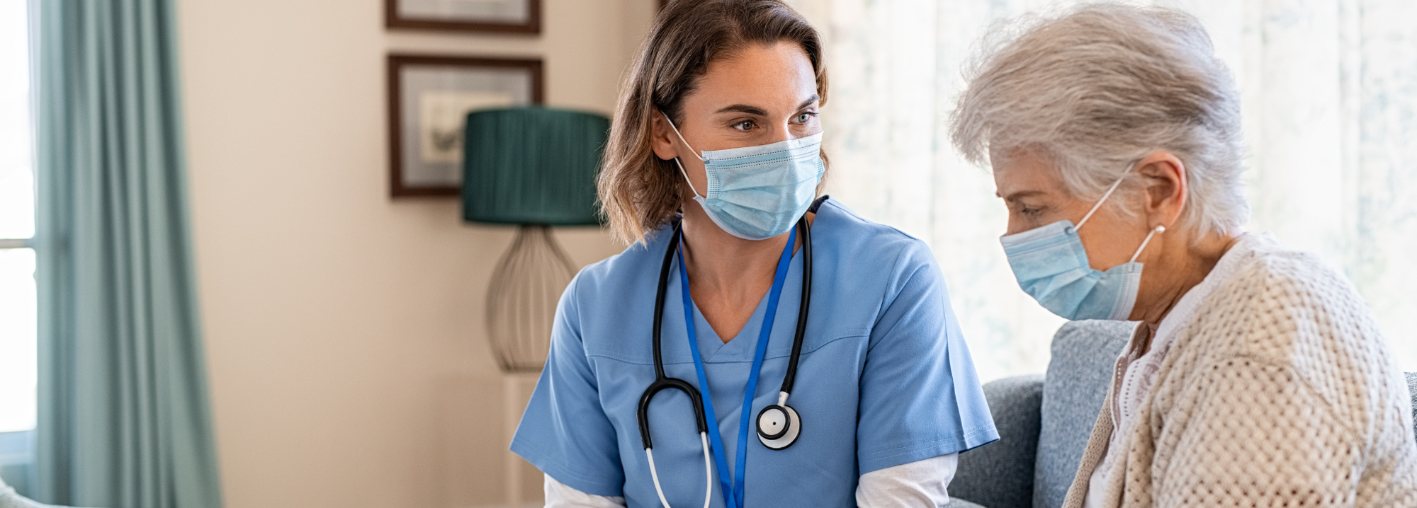 senior woman in facemask consults with nurse who is wearing a facemask