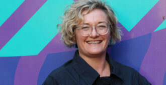 Professor Hannah Badland, Director, Social Equity Research Centre stands in front of colourful background