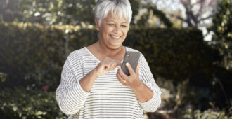 Happy senior woman using mobile phone in her garden