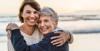 a senior mother hugging her adult daughter on the beach stock image