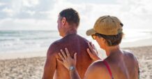 Mature aged couple putting on sunscreen at the beach
