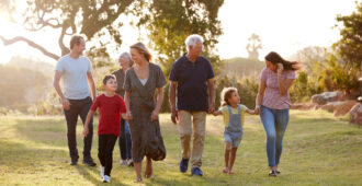 Multi-Generation Family Walking In Countryside Against Flaring Sun