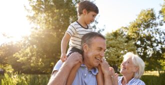Grandfather giving grandson a ride on shoulders in park