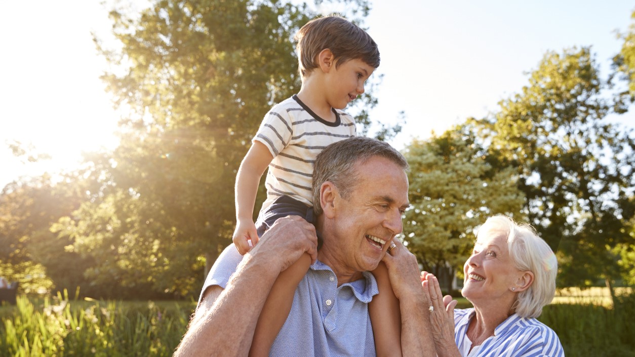 Grandfather giving grandson a ride on shoulders in park
