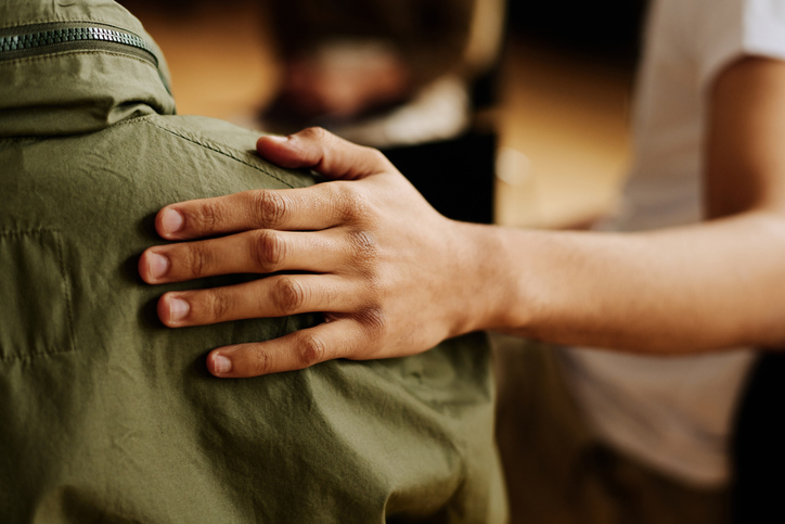 Hand of community worker consoling a young man with psychological distress