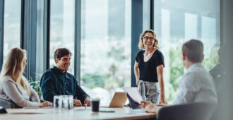 Office colleagues having casual discussion during meeting in conference room. Group of men and women sitting in conference room and smiling.