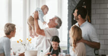 A family gathers around a kitchen table, sharing a meal and enjoying each other's company.