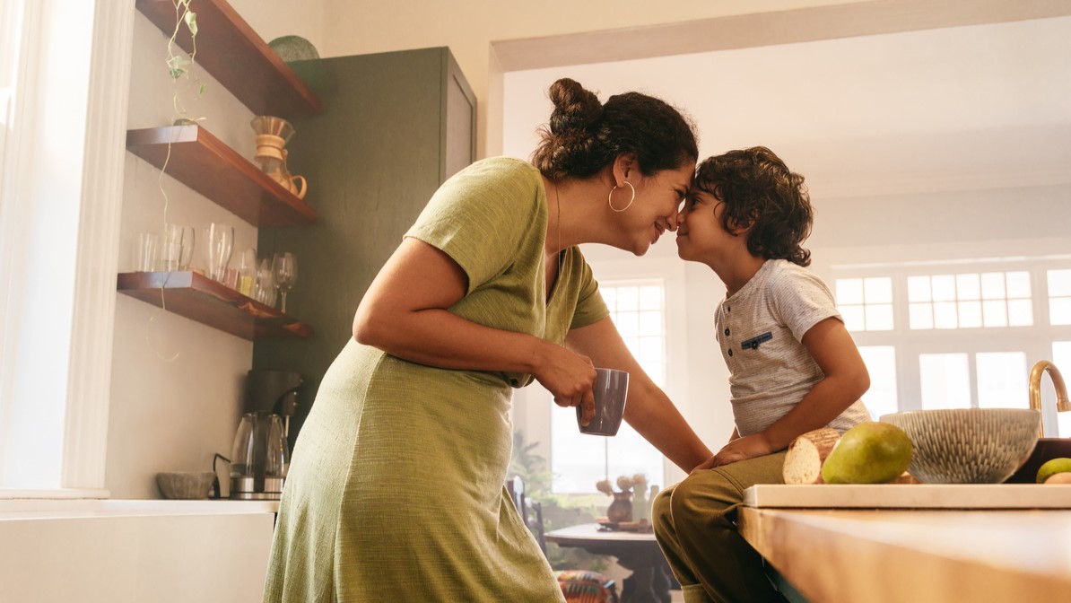 Mother and toddler son being affectionate in the kitchen